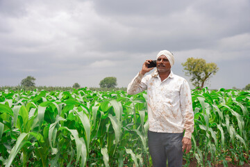 Young farmer working in a cornfield, inspecting and tuning irrigation center pivot sprinkler system...