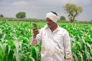 Young farmer working in a cornfield, inspecting and tuning irrigation center pivot sprinkler system...