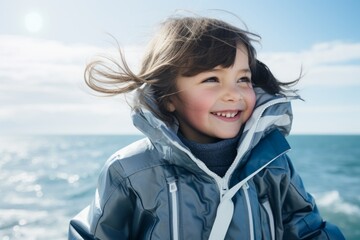 Portrait of a cute little girl in a blue jacket on the beach