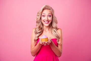 Portrait of adorable cheerful girl toothy smile hands hold little tasty cake muffin isolated on pink color background