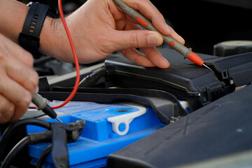 technician checks the battery using a voltmeter capacity tester,auto mechanic uses a multimeter voltmeter to check the voltage level in a car battery