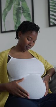 Portrait of pregnant woman touching belly at home