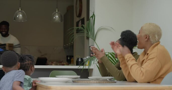 Man serving boxes of pizza to family at table