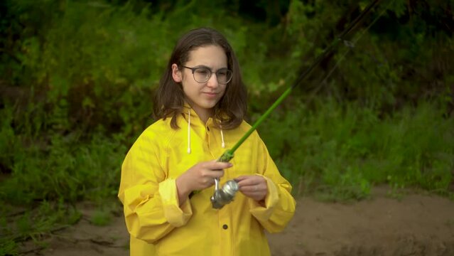 A young woman is fishing on the river bank. 