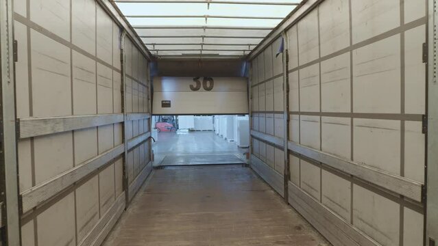 Roll up door opening view inside of cargo container zoom in and zoom out handheld shot. Warehouse shipping container indoors with no people