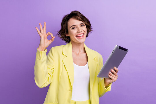 Photo of funny successful business assistant lady show okey sign holding tablet alrighty good job isolated on violet color background