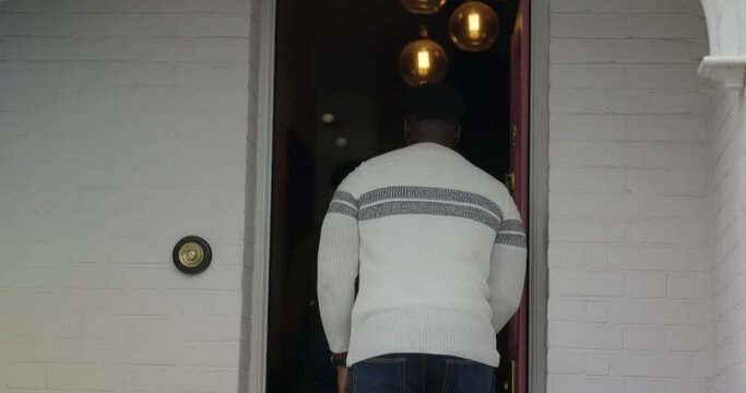Rear view of man opening doors and entering house