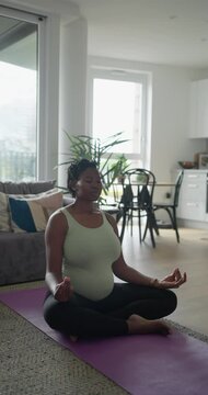 Pregnant woman practicing yoga on exercise mat at home