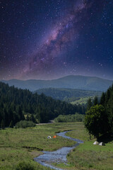 Majestic view of mountains valley river and camping tents. Milky Way night sky. © prystai