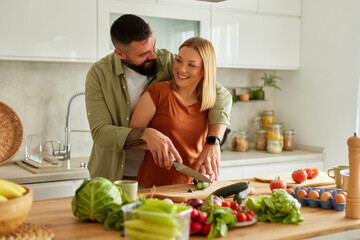 Affectionate couple cutting vegetable in the kitchen