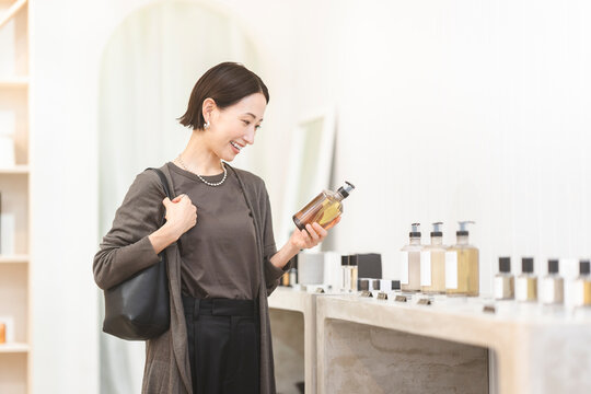 店舗で商品を手に取り選んでいる日本人女性/ショッピング
