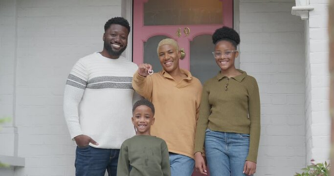 Portrait of smiling family standing in front of house with house key