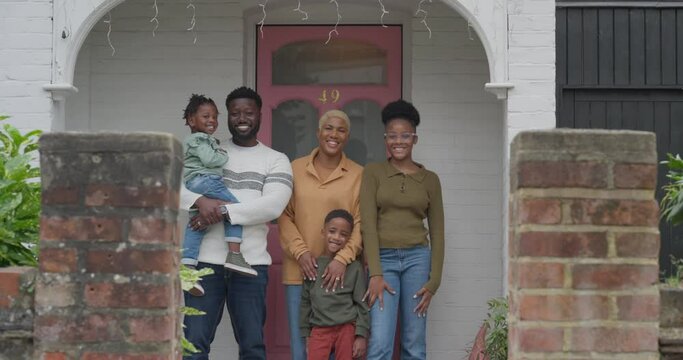 Portrait of smiling family standing in front of house