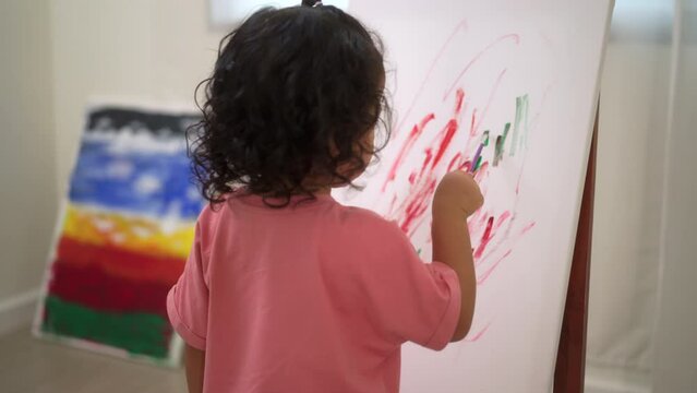 
Happy moment little cute girl creating and water color painting activity with paint brushes on frame canvas at living room. Kids activity. Child physical, Emotional, Cognitive development concept.