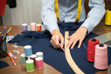 Female clothing designer placing pattern on fabric in home.