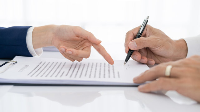 Solicitor pointing at insurance contract showing male client where to write signature sign sale purchase employment agreement at meeting make financial business deal, bank loan service, close up view