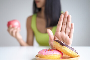 Diet and dieting. Beauty slim female body confuse donut. Woman in exercise clothes achieves weight...