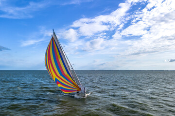 Drone shot of the bow of a sailboat healed over with a bright colourful genoa, gennaker, or...