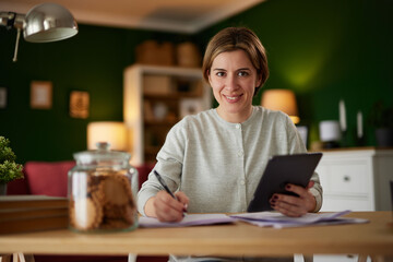 Women using digital tablet to check her finances at home office