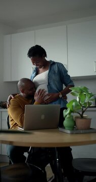 Man working on laptop when pregnant woman entering to kitchen