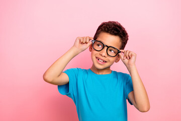 Photo portrait of charming small boy touch specs look curious empty space wear trendy blue garment isolated on pink color background © deagreez