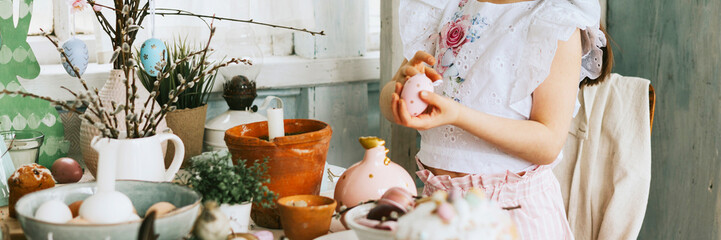 pretty little Armenian girl helps with baking for Easter on veranda on sunny spring day decorated...
