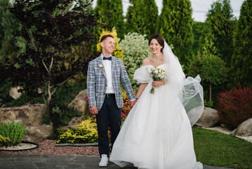 Bride and groom happiness outdoors. Newlyweds with a wedding bouquet standing on wedding ceremony...