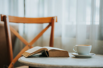 coffee cup, phone and books on the table by the white curtain window