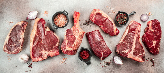 Variety of Raw Black Angus Prime meat steaks T-bone, tomahawk, New York steak. Set raw marbled beef strip loin steaks. place for text, top view - obrazy, fototapety, plakaty