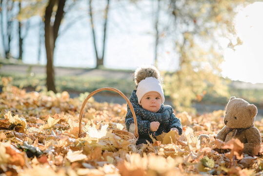 Little girl have picnic, walk in forest. Child playing and sits on blanket on yellow leaves in park. Family with kid spending time at sunset. Autumn holiday in nature. Spring mood photo with sunlight