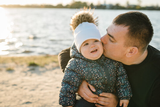 Dad kiss daughter walk in park. Father hugging child near lake in nature. Family spending time together at sunset on vacation. Upper half. Concept of autumn holiday. Closeup. Father's, children's day.