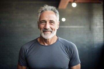 Portrait of a handsome senior man with grey hair standing in a gym