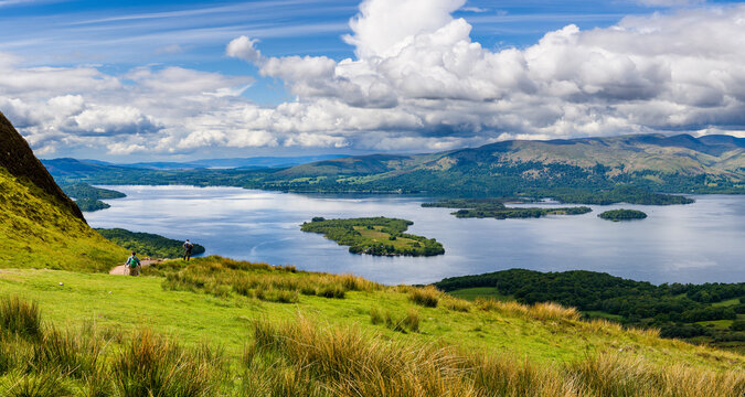 Hikers descending Conic Hill towards Loch Lomond with beautiful mountain scenery