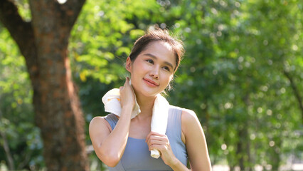 Portrait young asian woman attractive smiling and use white towel resting after workout. Smiling sporty young woman working out outdoors and looking at camera. Healthy lifestyle well being wellness