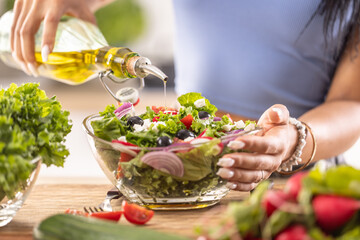 The final preparation of a healthy salad and at the end the woman pours olive oil