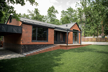 modern brick house with large windows, green lawn, cottage town - obrazy, fototapety, plakaty