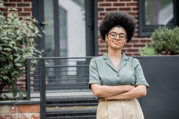 confident african american real estate agent in eyeglasses looking at camera outdoors