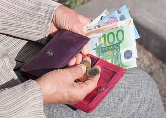 Euro banknotes and coins in the hands of an elderly woman. - obrazy, fototapety, plakaty