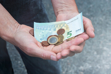 Euro banknotes and coins in female hands, selective focus.