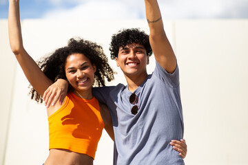 smiling young couple with arms raised