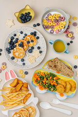 Cute plates with a variety of children's food. Vegetables, nuggets, french fries, pancakes, cereal and juice. Creative serving for baby.  Concept of kids menu, nutrition and feeding.