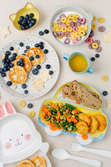 Cute plates with a variety of children's food. Vegetables, nuggets, french fries, pancakes, cereal and juice. Creative serving for baby.  Concept of kids menu, nutrition and feeding.