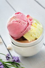 A variety of balls of ice cream in cones with chocolate, vanilla and strawberries