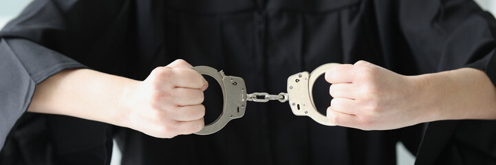 Judge sitting at table with wooden judge gavel and holding handcuffs.