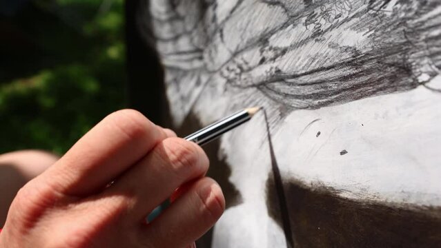 Female Mid Adult Artist Drawing an Owl with a pencil on paper close up
