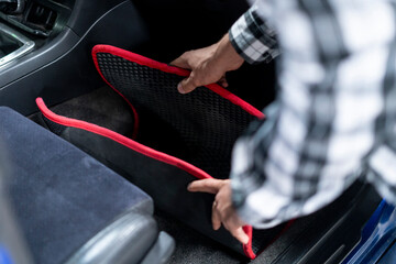 a person takes a dirty car mat to wash