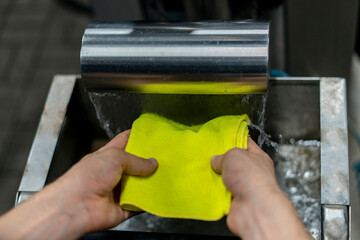 a man at a self-service car wash washes and dries microfiber in water