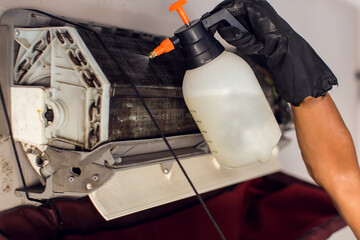  Cleaning the air conditioner by spraying. man washes off a special foam for cleaning air...