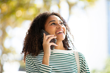 smiling young woman talking with cellphone and looking up