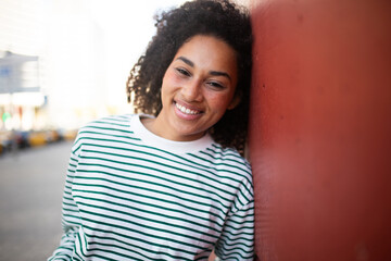 Fototapeta premium happy young african american woman leaning against wall